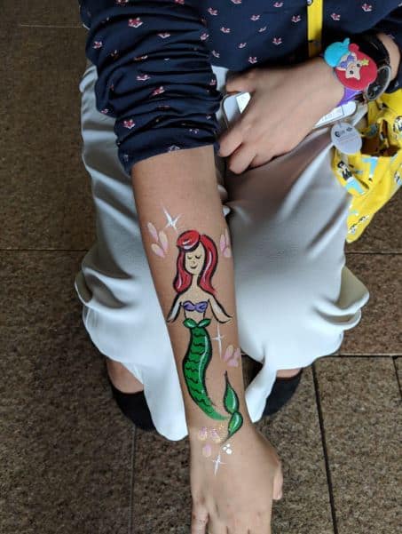 little mermaid face painting done on girls arm
